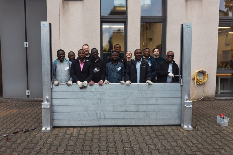 Group posing behind the semi-erected mobile flood protection wall.